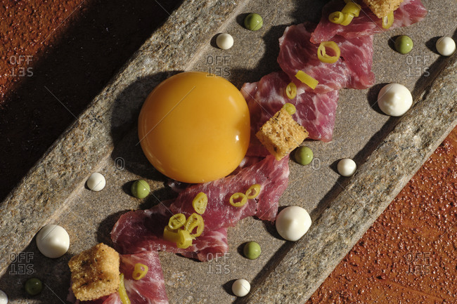 Top view of zest with meat and single egg yolk arranged on plunk in sunbeam