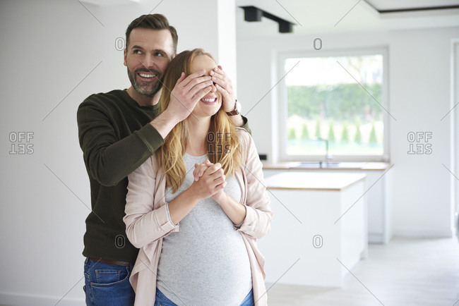 Man surprising pregnant woman in empty flat