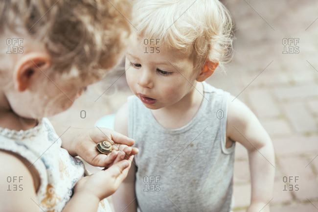 Little boy and girl looking at a snail in hand