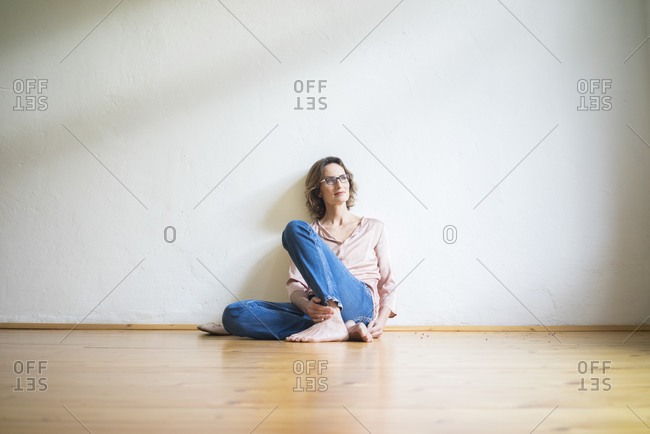 Mature woman sitting on floor in empty room thinking
