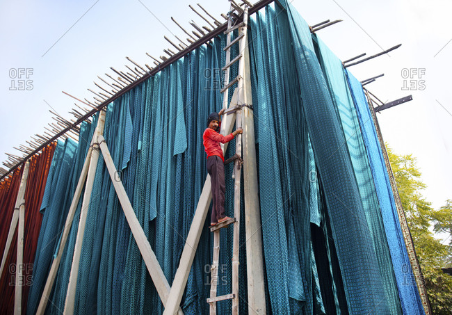 Jaipur, India - January 2, 2020: Low angle view of textile dying worker on ladder