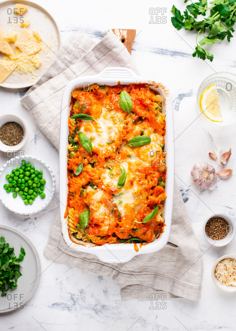 Baked macaroni and cheese casserole dish with green peas and spinach