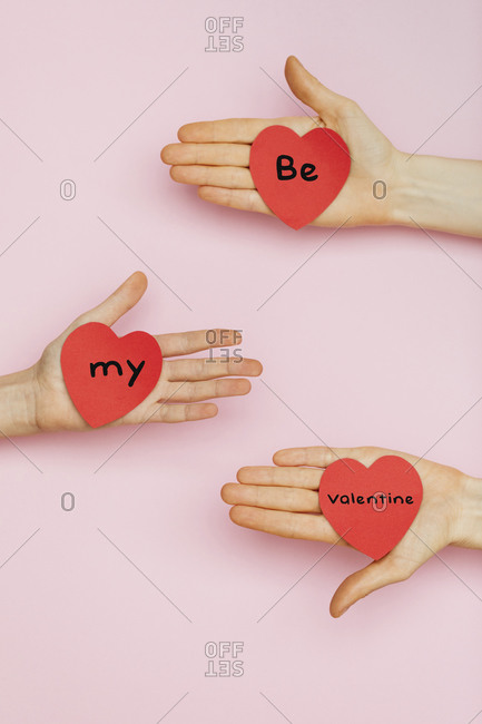 Three hands holding Valentine hearts