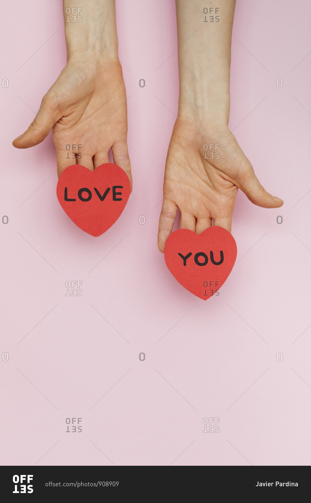 Hands holding Valentine hearts that read 