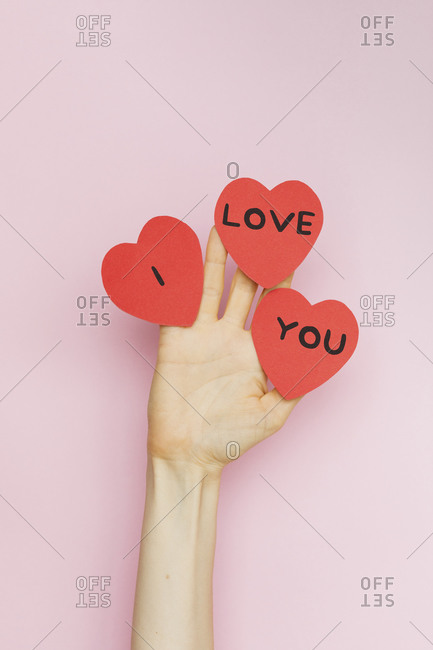 A hand holding Valentine hearts that read 