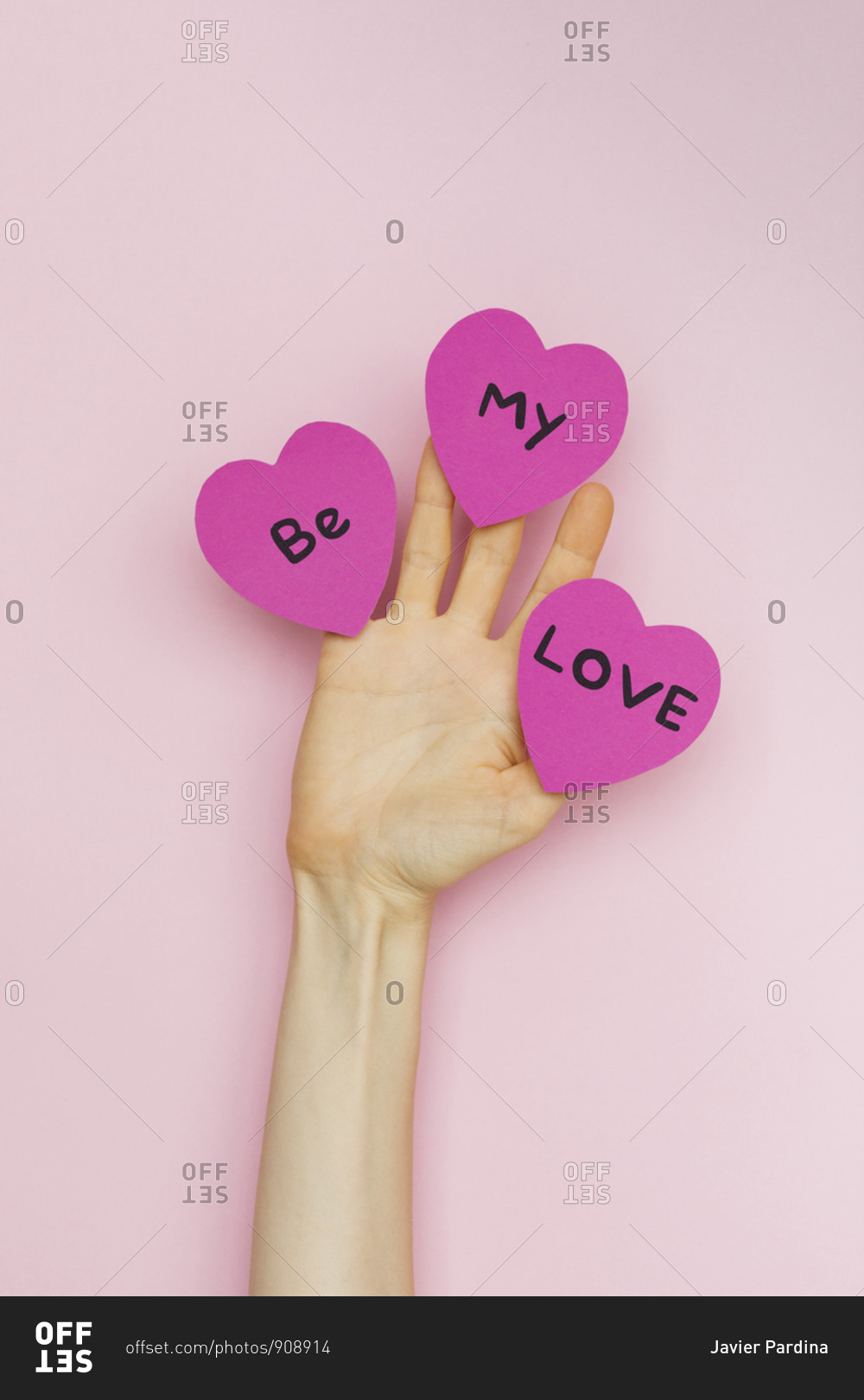 A hand holding Valentine hearts that read 