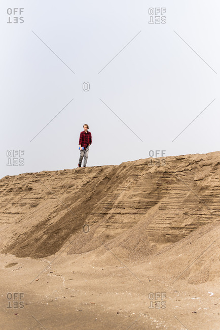 Teenager walking along top of sand bluff at beach