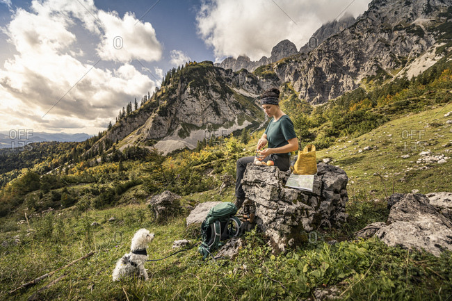 Woman with dog on a hiking trip at Wilder Kaiser having a break- Kaiser mountains- Tyrol- Austria