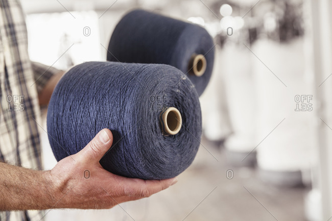 Close-up of man holding cotton reels in a textile factory