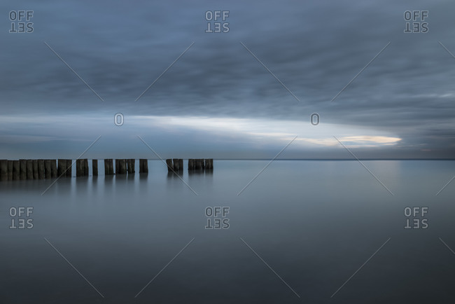 A wooden pile trail points towards the horizon between sky and sea, Bibione, Adriatic sea, Veneto, Italy, Europe
