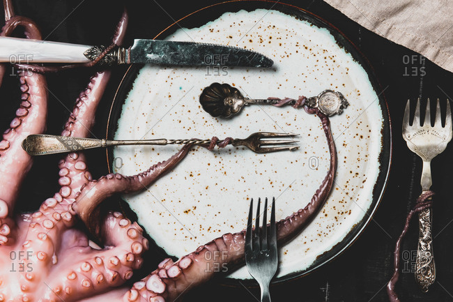 octopus holds forks and knife with tentacles on a table