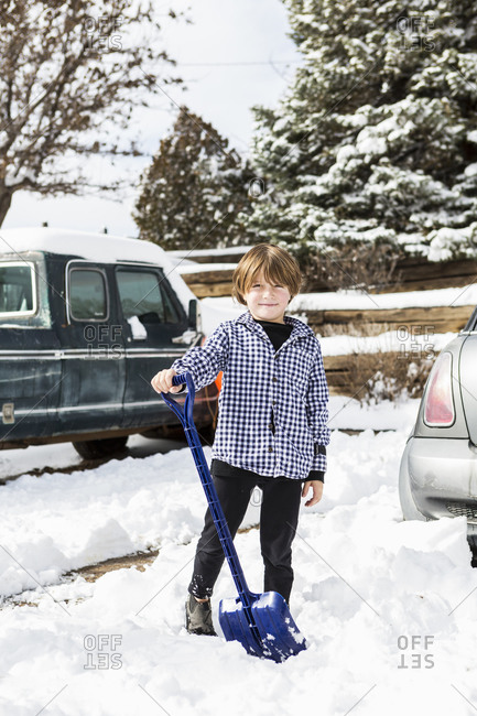 A young boy shoveling snow in driveway