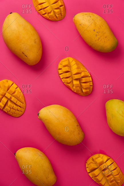 Flat lay mango fruit sliced in half cubes in pink colorful cardboard background