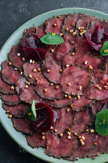 Overhead savory meat carpaccio served with boiled beetroot on plate in restaurant