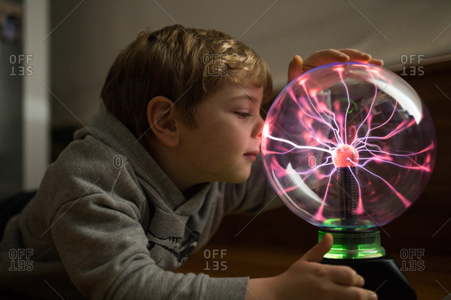 Boy looking at mysterious glass lightening lamp on table