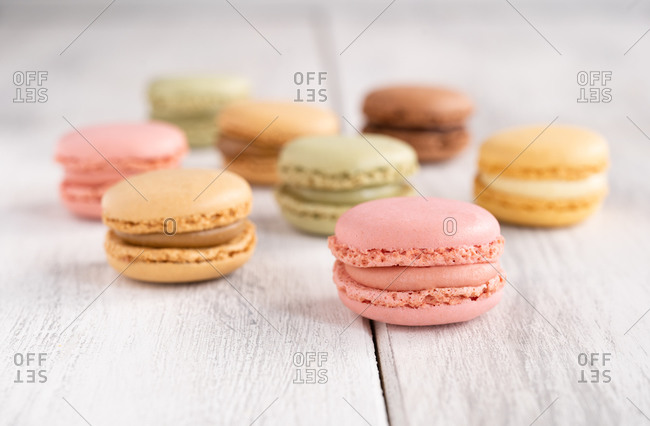 Colorful tasty macaroons stacked in pile against wooden white surface