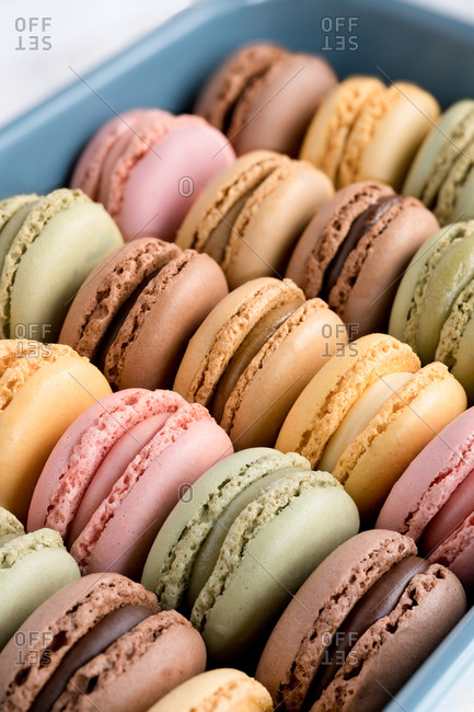 Colorful tasty macaroons displayed inside blue container