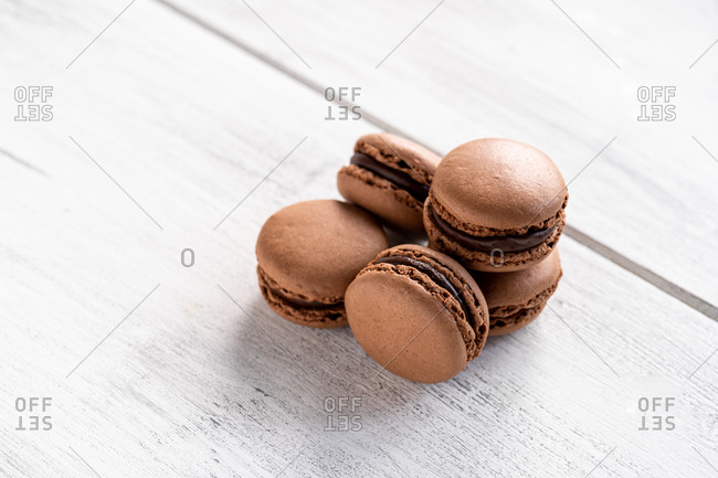 Brown tasty macaroons stacked in pile against wooden white surface