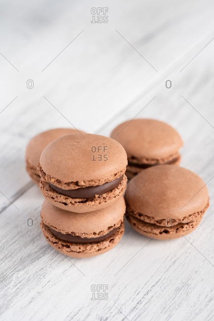 Brown tasty macaroons stacked in pile against wooden white surface