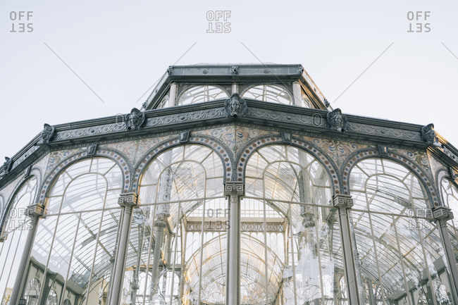 Geometrical ancient castle with glass windows reflecting trees, Palacio de Cristal, Retiro Park, Madrid, Spain