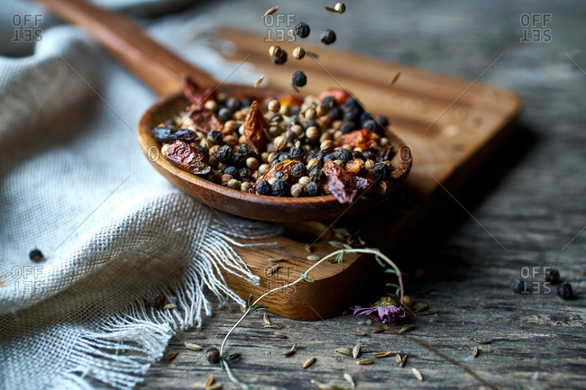 Spice fragrant mix of fresh spices and dried berries on wooden spoon on linen on wooden stand at table