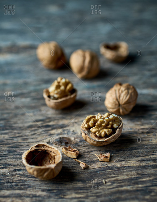 From above appetizing fresh yellow half peeled walnuts and broken empty walnut shells on wooden table