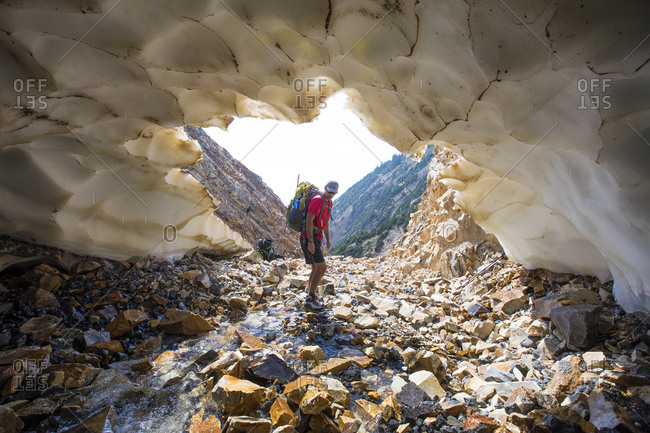 Backpacker approaches entrance to snow tunnel