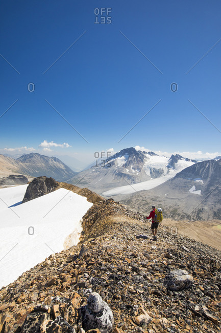 Rear view of hiker crossing rocky ridge on sunny day.