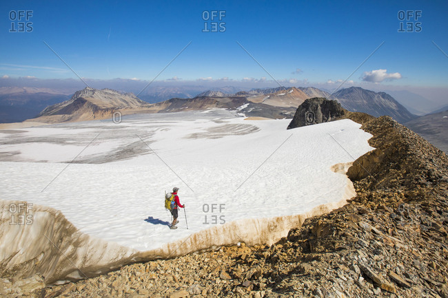 high angle of backpacker hiking across tip of huge glacier.