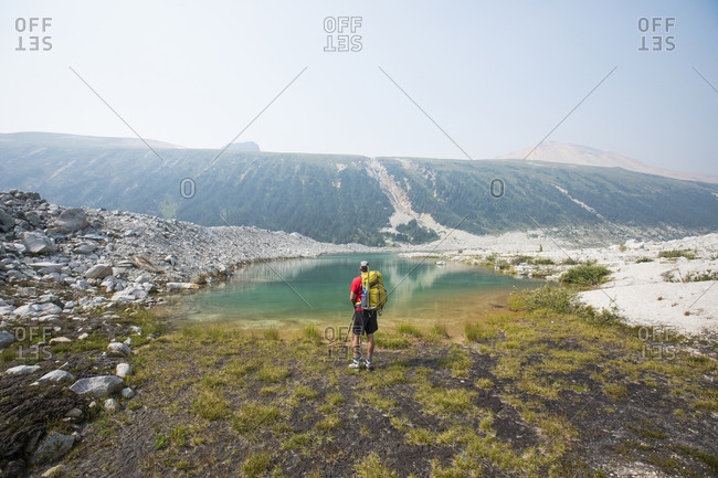 Rear view of backpacker looking at alpine tarn.