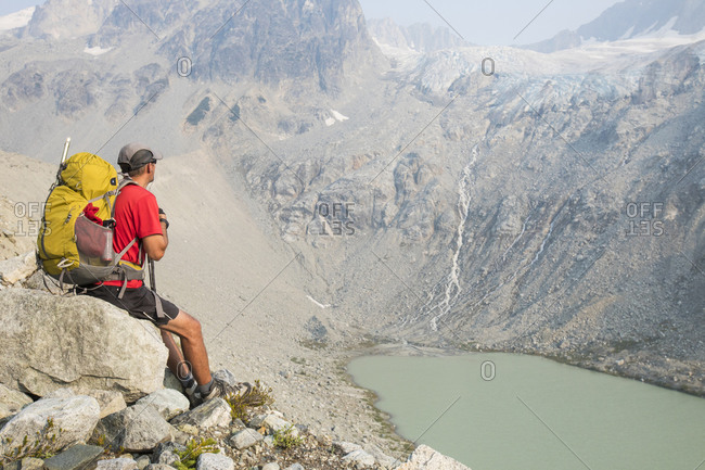 Hiker sits on rock with view of waterfall.