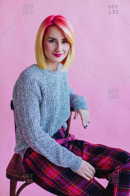 Portrait of a cool girl with dyed hair sitting on a chair