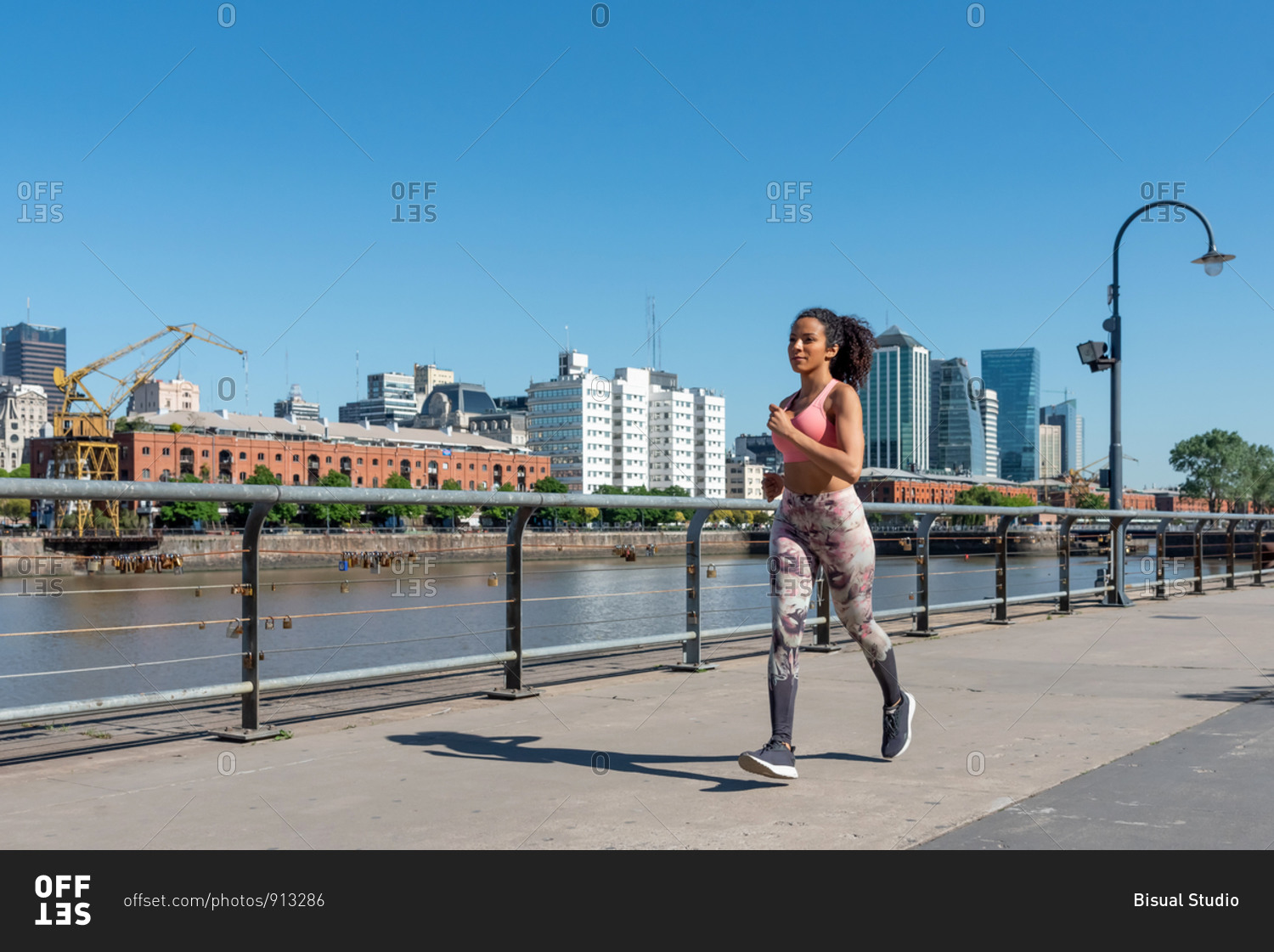 Latin American woman with a pink outfit jogging in Puerto Madero, Buenos Aires