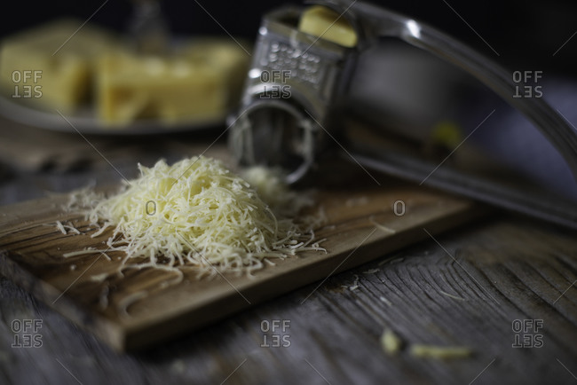 Grated onion near metal standing grater on wooden cutting board