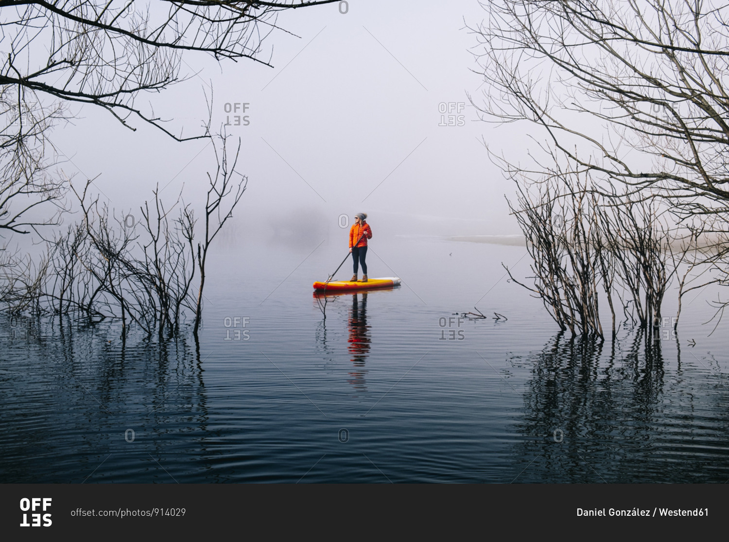 Woman stand up paddle surfing on a lake in the fog
