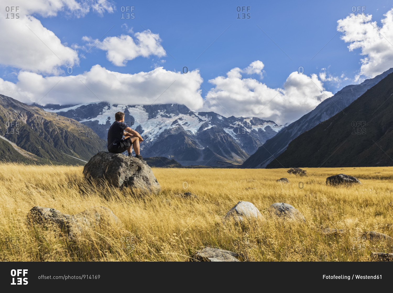 New Zealand- Oceania- South Island- Canterbury- Ben Ohau- Southern Alps (New Zealand Alps)- Mount Cook National Park- Aoraki / Mount Cook- Man sitting on boulder in mountain landscape