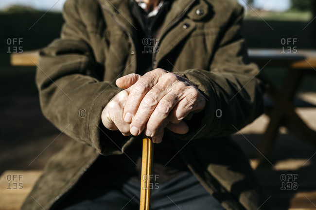 Old man\'s hands resting on his cane- close up