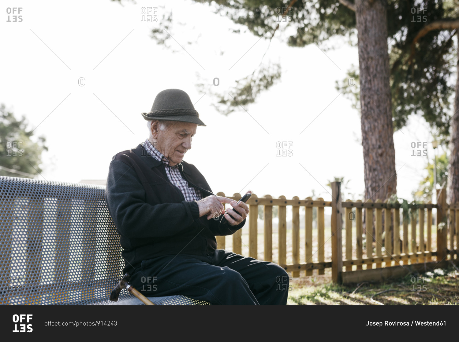 Old man with- sitting on bench- using smartphone