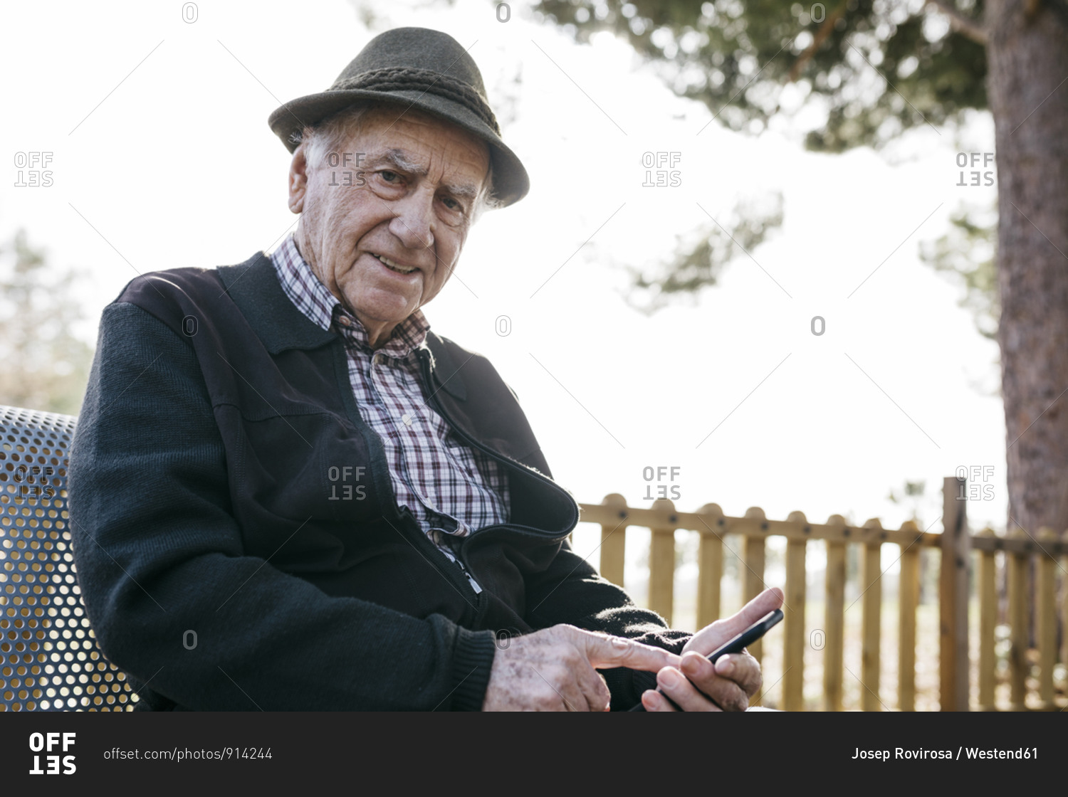 Old man with- sitting on bench- using smartphone
