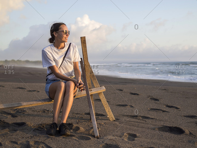 Woman sitting on rack on the beach at evening twilight- Kedungu beach- Bali- Indonesia