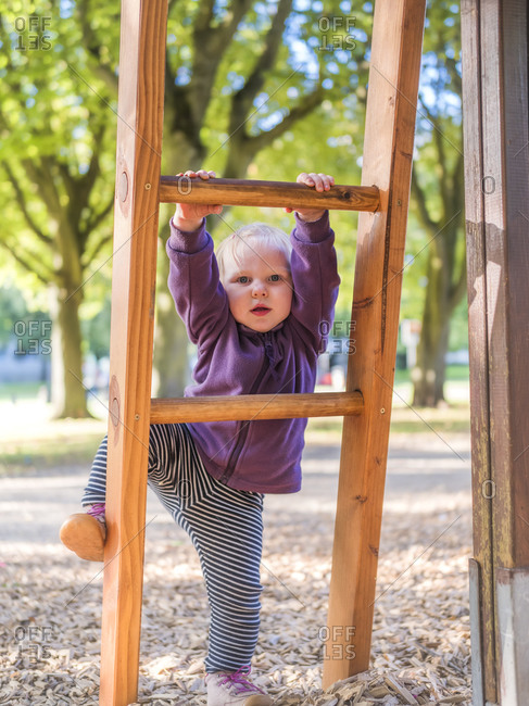 Portrait of toddler girl climbing on ladder at playground