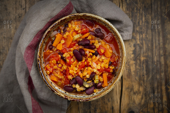 Bowl of vegan chili with red lentils- celery sticks- kidney beans- tomatoes and carrots