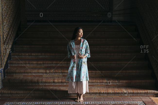 Portrait of beautiful young woman wearing a kimono standing at stairs