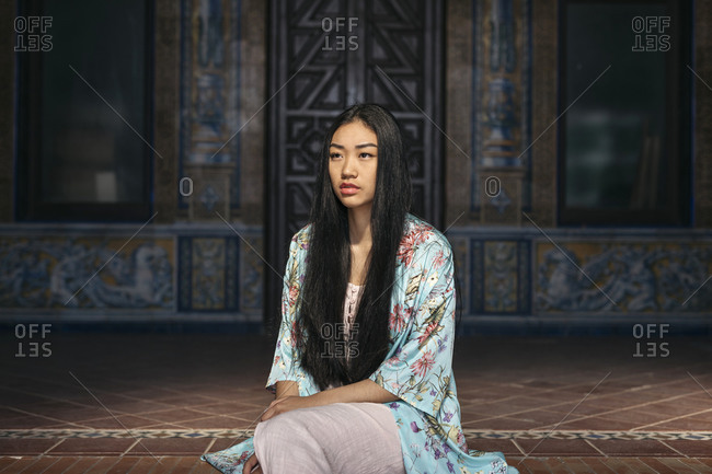 Portrait of beautiful young woman sitting on steps wearing a kimono