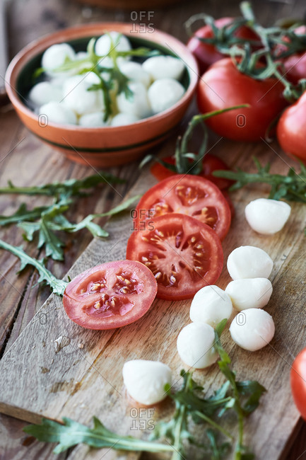 Mozzarella cheese balls on the table with sliced tomato and arugula