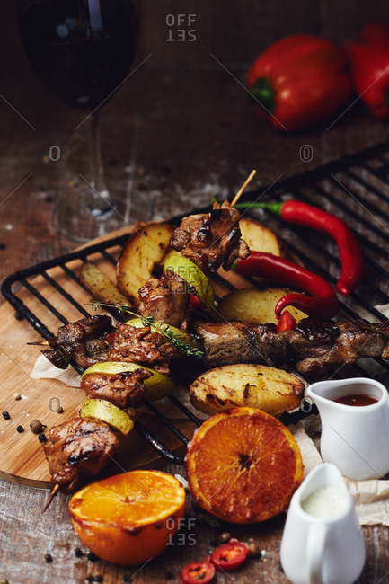Pork kebab on a wooden skewer with vegetables and oranges with barbecue sauce pepper and french fries