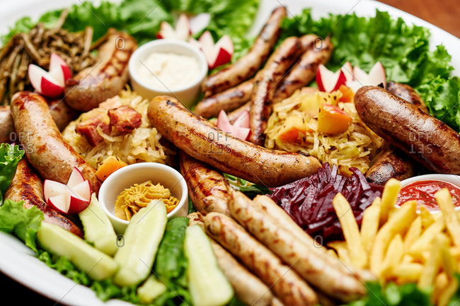 Assorted grilled sausages on the barbecue grill with vegetables and salad, radish cucumber