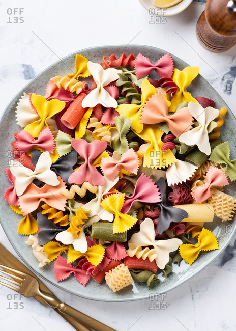 Overhead view of plate with uncooked colorful various types Italian pasta