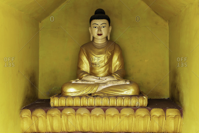 A gold-coloured Buddha statue in a yellow alcove in a temple opposite to Shwezadi Monastery, Sittwe, Rakhine, Myanmar (Burma), Asia