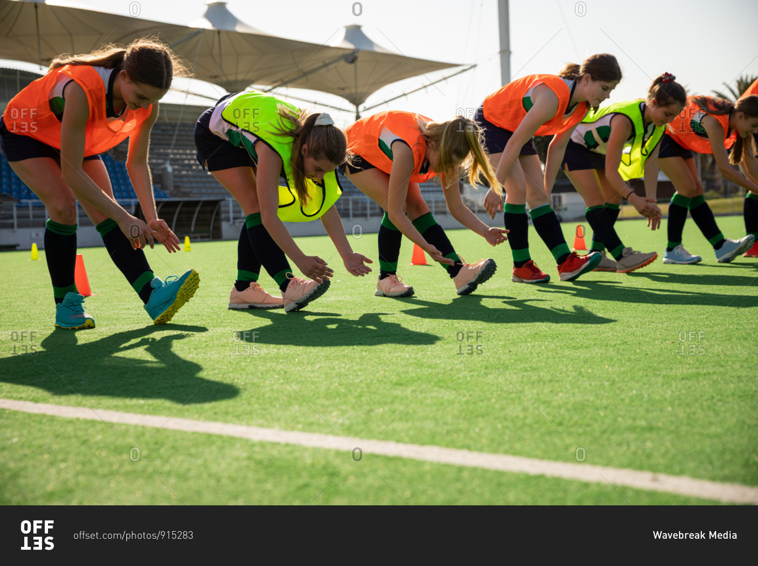 Side view of a group of female Caucasian field hockey players, training
